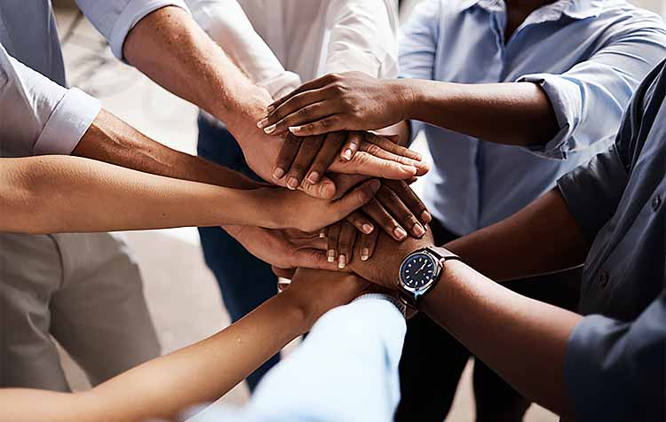 Group of businesspeople stacking their hands at work.