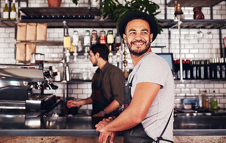 Coffee shop owner with barista working in behind